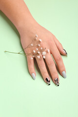 Woman with press-on nails and flowers on green background