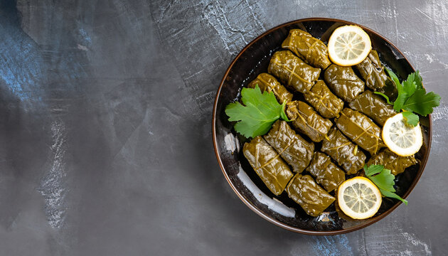 Dolma - stuffed grape leaves with rice and meat on a dark background, view from above, copy space. Traditional Greek, Caucasian and Turkish cuisine