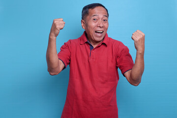 Elderly happy strong man 60s in casual t-shirt do winner gesture clench fist celebrating isolated...