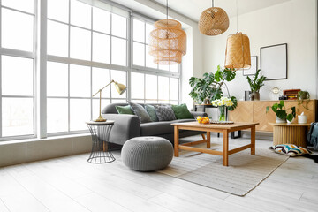 Interior of stylish living room with cozy sofa and table near big window