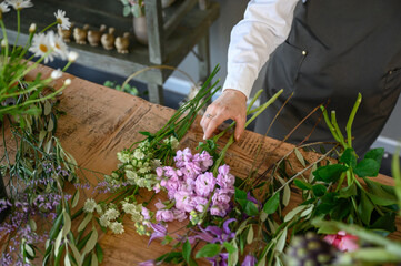 Unrecognizable florist making bouquet of buds on table