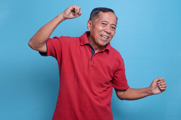 Portrait of cheerful senior man rejoicing having fun attainment isolated over blue color background