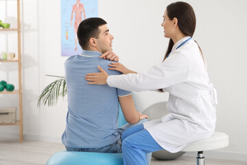 Female doctor checking posture of young man in clinic