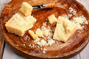 Plate with pieces of tasty Parmesan cheese on light wooden background, closeup