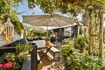 Fototapeta na wymiar an outdoor living area with patio furniture and umbrellas on the roof, surrounded by lush green plants and flowers