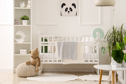 Stylish interior of children's room in white tones with baby bed and shelving unit