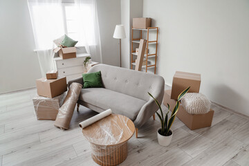 Fototapeta na wymiar Sofa with rolled carpet and cardboard boxes in living room on moving day