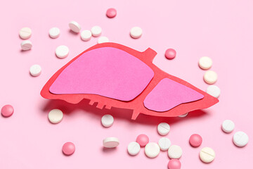 Paper liver with pills on pink background