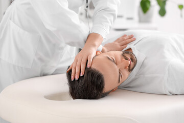 Female physiotherapist working with young man on couch in rehabilitation center, closeup