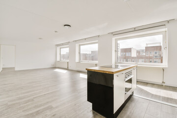 an empty room with white walls and wood flooring, there is a large kitchen island in front of the window