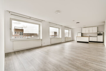 an empty living room with wood flooring and white cabinetd appliances on the windows overlooking out onto the street