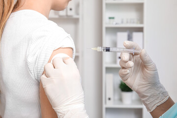 Female doctor giving patient injection in clinic, closeup