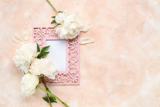 Composition with blank picture frame and beautiful peony flowers on color background