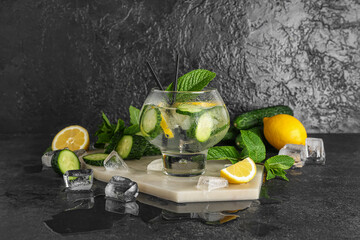 Glass of lemonade with cucumber and mint on black background