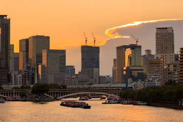 Orange sunset glow over Osaka City with Tenjin Festival boats on river