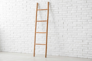Wooden ladder near white brick wall in room
