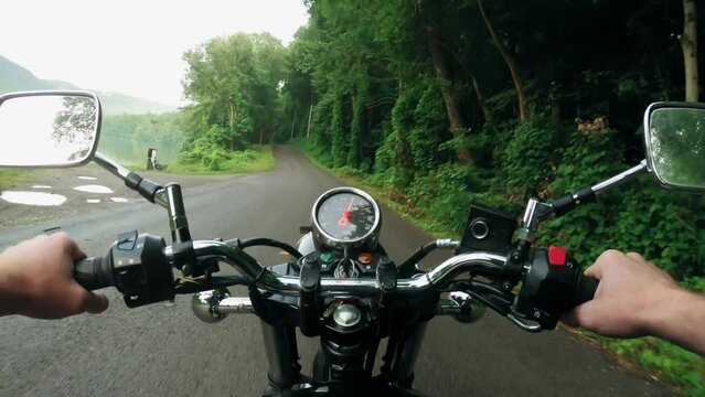 young and adventurous man driving down the road on a motorbike on his morning commute to work through the contryside