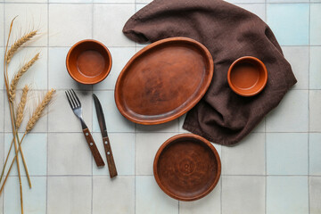 Set of clean wooden dishes and cutlery on tiled table