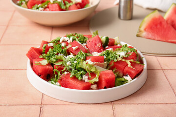 Plate of tasty watermelon salad on beige tile background