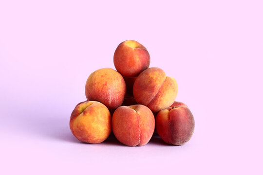 Heap of sweet peaches on lilac background