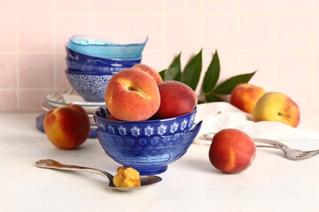 Bowl with sweet peaches on white table