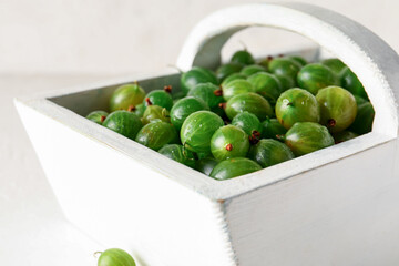 Basket with fresh gooseberries on white background, closeup