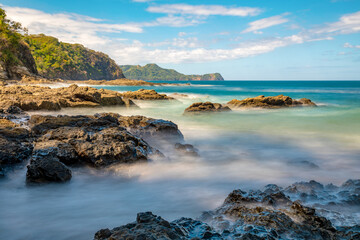 Long exposure, pacific ocean waves on rock in Playa Ocotal, El Coco Costa Rica. Famous snorkel beach. Picturesque paradise tropical landscape. Pura Vida concept, travel to exotic tropical country.