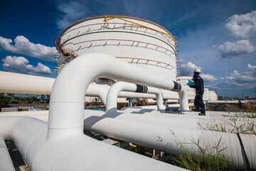 Male worker inspection at steel long pipes and pipe elbow in tank oil station oil factory during refinery valve of visual check record pipeline oil and gas