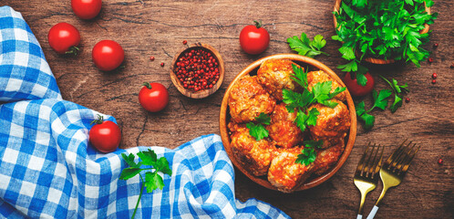 Pork and beef meatballs in tomato sauce with parsley in wooden bowl on rustic wood kitchen table....
