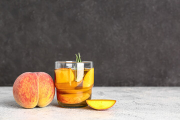 Glass of fresh peach lemonade with rosemary on white table