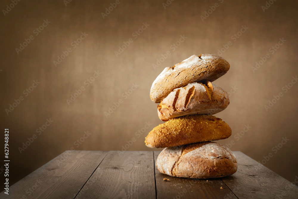 Aufkleber different whole loaves of fresh bread with crispy crust on wooden table in bakery with copy space