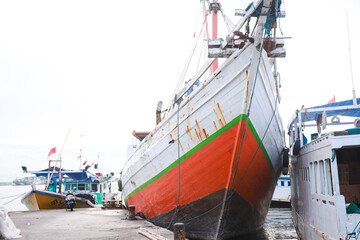 Fototapeta premium Several wooden boats and cargo ships moored at the traditional port while waiting for loading and unloading