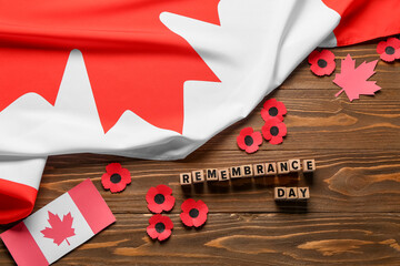 Fototapeta premium Poppy flowers with flags of Canada on wooden background. Remembrance Day