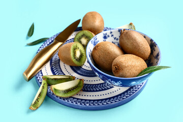 Bowl with fresh kiwi and leaves on turquoise background