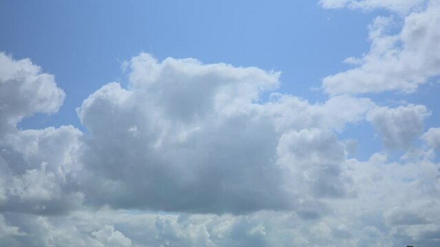 Fluffy white clouds blowing by with blue sky on sunny summer day, time lapse 30x. Soy FX30.