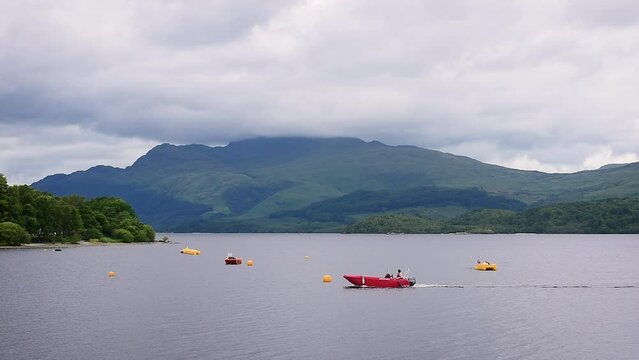 Speedboat on Loch Lomond lake surrounded by mountains, Scotland