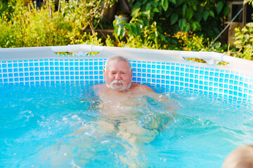 An elderly man bathes in a pool. 