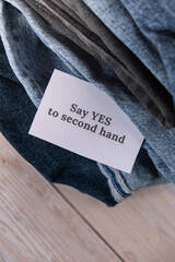 SAY YES TO SECOND HAND text on paper note on Jeans clothes assortment Second hand sustainable shopping. Capsule minimal wardrobe. Sustainable fashion overconsumption, conscious buying consumption