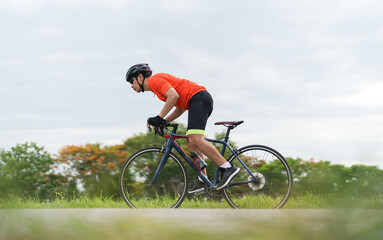 Young guy wearing sport clothing, Cyclist pedaling on a racing bike outdoors in a sunny day