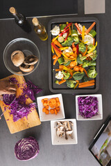 Overhead of senior biracial woman cutting cabbage on table with vegetables in kitchen at home