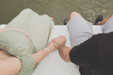 Expecting Couple Holding Hands while Sitting on Dock