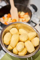 Peeled potatoes ready for cooking. Chicken breast in pieces with potatoes and carrot in a saucepan simmer on low heat. Home cooking. Healthy food, cooked without oil and salt.