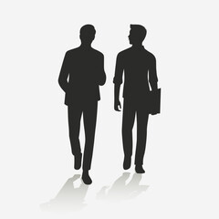 Silhouette of two men walking while chatting