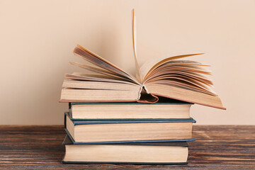 Stack of books on wooden table against beige background