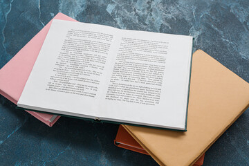 Open and closed books on dark blue table