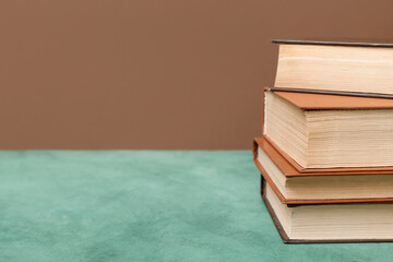 Stack of books on green table against brown background