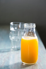 Bottle of Orange juice on a rustic wooden table.