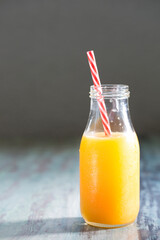 Bottle of Orange juice on a rustic wooden table.