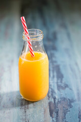 Bottle of orange juice with red and white straw.