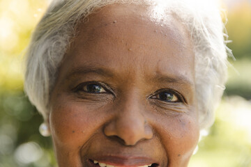 Portrait close up of happy senior biracial woman smiling in sunny garden at home